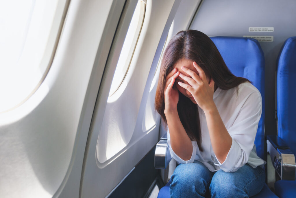 woman with her head in her hands sitting on airplane