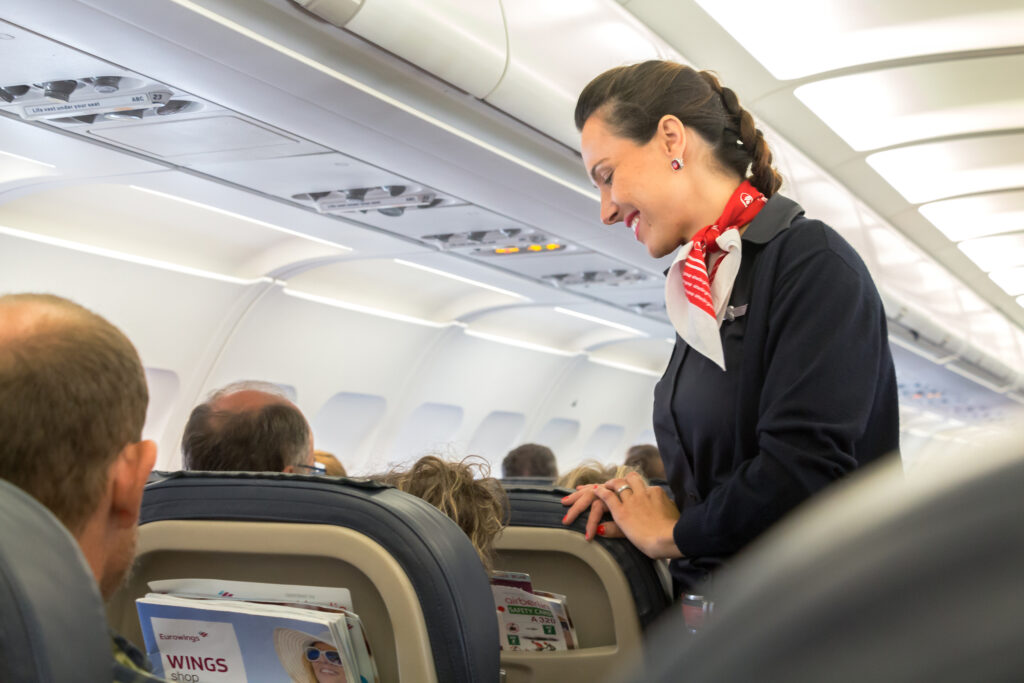 flight attendant helping passenger on plane